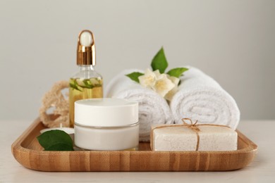 Composition with beautiful jasmine flowers and skin care products on white table