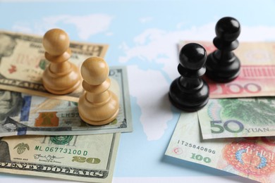 Chess pieces, yuan and dollar banknotes on world map. Trade war concept