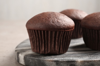 Delicious fresh chocolate cupcakes on grey marble board, closeup