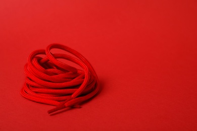 Bright shoe lace on red background. Space for text