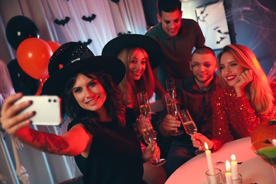 Group of friends taking selfie at Halloween party indoors