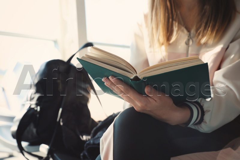 Young woman reading hardcover book indoors, closeup