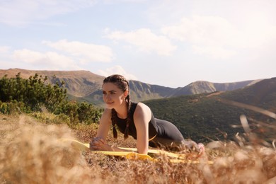 Beautiful young woman doing yoga in mountains on sunny morning