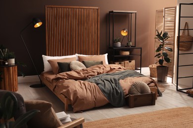 Stylish room interior with large bed near brown wall