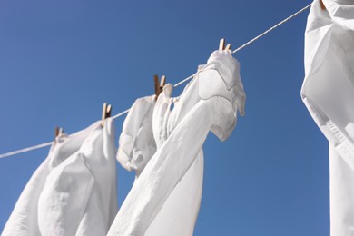 Photo of Clean clothes hanging on washing line against sky, low angle view. Drying laundry