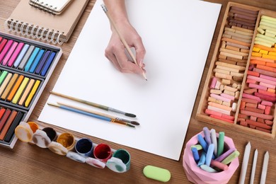 Artist drawing picture with pastel pencil at wooden table, closeup