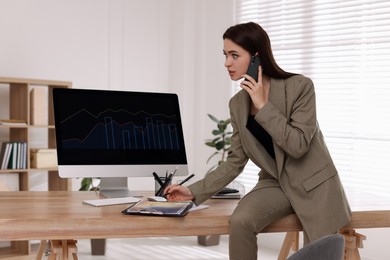 Businesswoman talking on phone while working in office. Forex trading