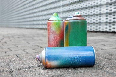 Used cans of spray paints on pavement, closeup