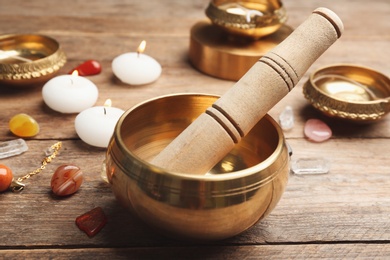 Composition with golden singing bowl and mallet on wooden table. Sound healing