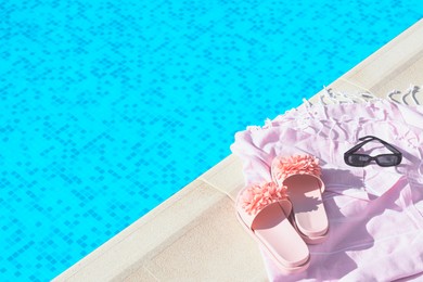 Photo of Pink blanket with slippers and sunglasses near outdoor swimming pool on sunny day, space for text