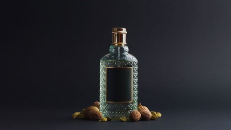 Photo of Bottle of luxurious perfume and spices on black background