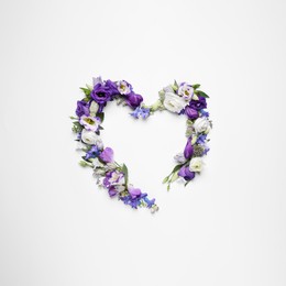 Beautiful heart made of different flowers on white background, top view