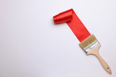 Brush painting with red ribbon on light background, top view. Space for text. Creative concept