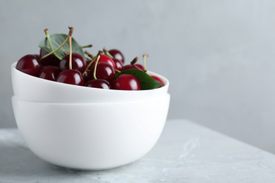 Sweet juicy cherries with leaves on grey marble table, closeup