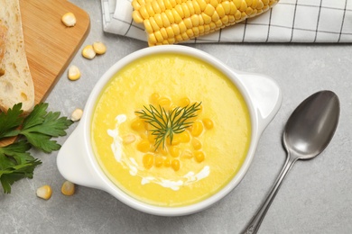 Delicious creamy corn soup served on grey table, flat lay