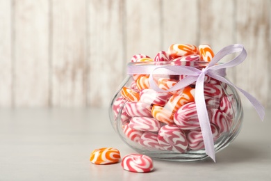 Sweet candies in glass jar on light grey table. Space for text