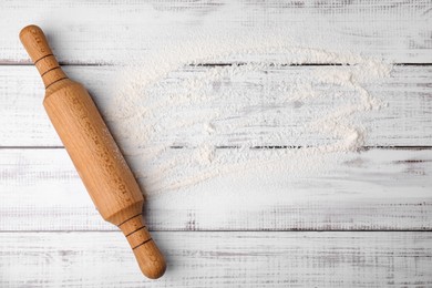 Flour and rolling pin on white wooden table, top view