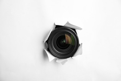 Photo of Hidden camera lens through torn hole in white paper