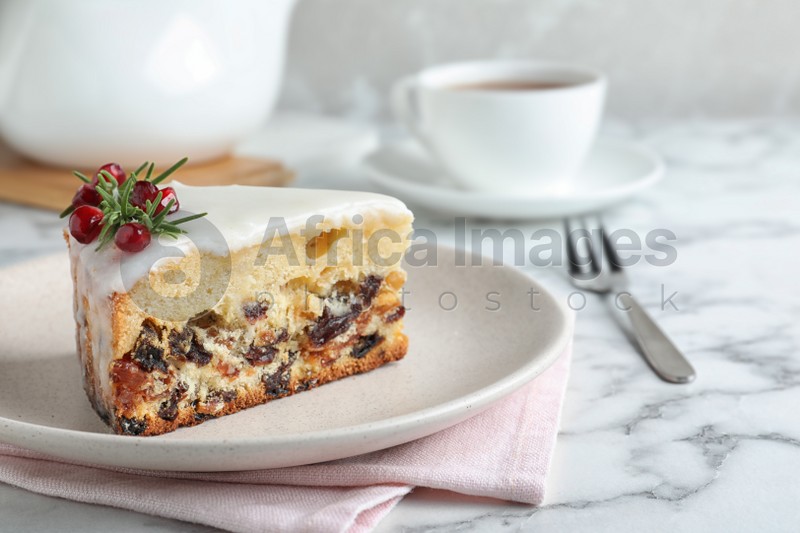 Photo of Slice of traditional Christmas cake decorated with rosemary and pomegranate seeds on white marble table