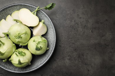 Whole and cut kohlrabi plants on grey table, top view. Space for text