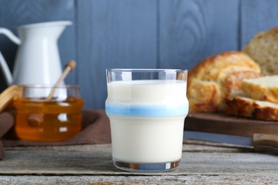 Photo of Glass with milk, honey and bread on rustic wooden table