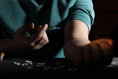 Photo of Addicted man taking drugs at black table, closeup