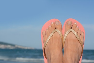 Woman wearing flip flops near sea, closeup. Space for text