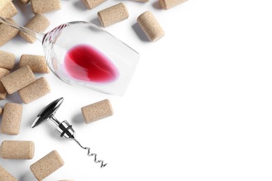 Photo of Corkscrew, glass with red wine and stoppers on white background, top view