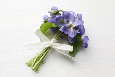 Beautiful wild violets on white wooden table, top view. Spring flowers