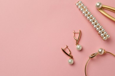 Elegant hair clips, bracelet and earrings with pearls on pink background, flat lay. Space for text