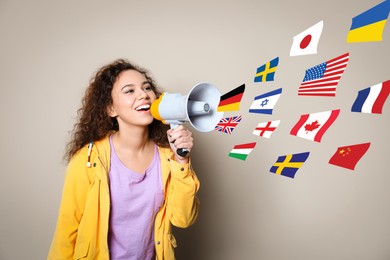Portrait of African American interpreter with megaphone and flags of different countries on beige background