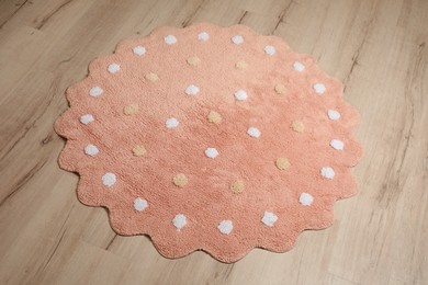 Round pink rug with polka dot pattern on wooden floor