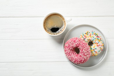 Photo of Yummy donuts with sprinkles and coffee on white wooden table, flat lay. Space for text