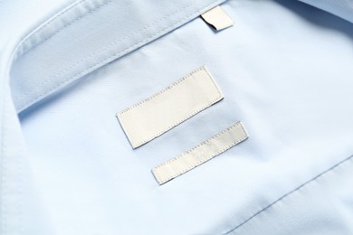 Blank clothing labels on light blue shirt, top view