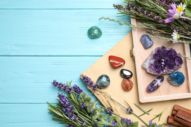 Gemstones and healing herbs on light blue wooden table, flat lay. Space for text