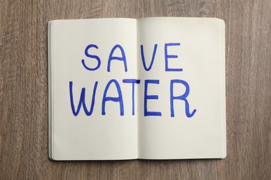 Photo of Notebook with phrase Save Water on wooden table, top view
