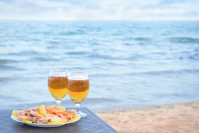 Cold beer in glasses and shrimps served with lemon on beach