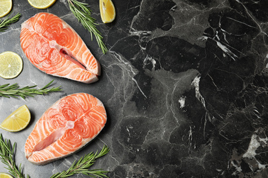 Flat lay composition with fresh raw salmon and rosemary on black marble table, space for text. Fish delicacy