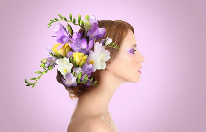 Pretty woman wearing beautiful wreath made of flowers on lilac background