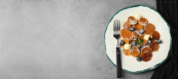 Cereal pancakes with blueberries and butter on light grey table, flat lay. Space for text