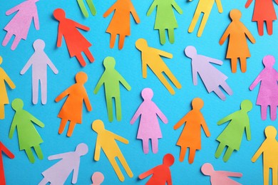 Photo of Many different paper human figures on light blue background, flat lay. Diversity and inclusion concept