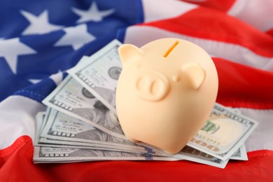 Piggy bank and dollar banknotes on American flag, closeup