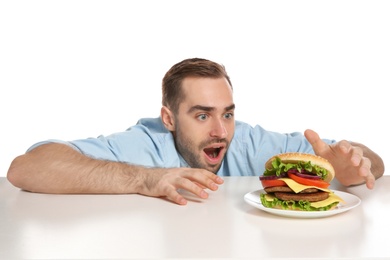 Young hungry man with tasty burger on white background