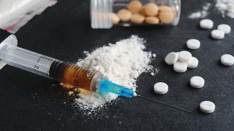 Photo of Syringe, pills and powder on black background, closeup. Hard drugs