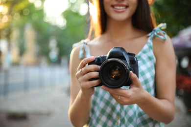 Young photographer with professional camera outdoors, closeup