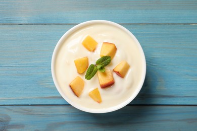Delicious yogurt with fresh peach and mint on light blue wooden table, top view