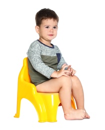 Portrait of little boy sitting on potty against white background