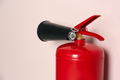 Fire extinguisher on pink background, closeup view