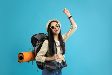 Photo of Happy female tourist with backpack on light blue background