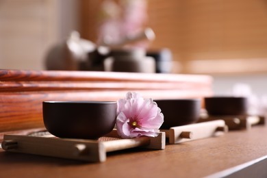 Cup with sakura flower for traditional tea ceremony on wooden table
